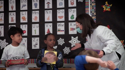 Teacher with a mask is talking to students