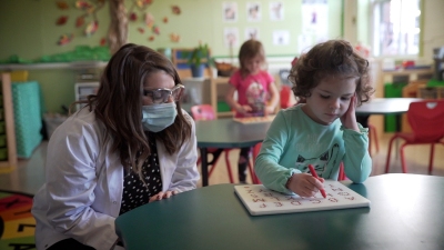 student is painting in front of her teacher