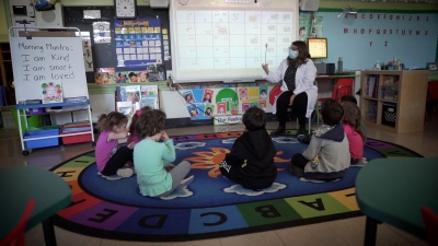 students sit on the floor and look at their teacher